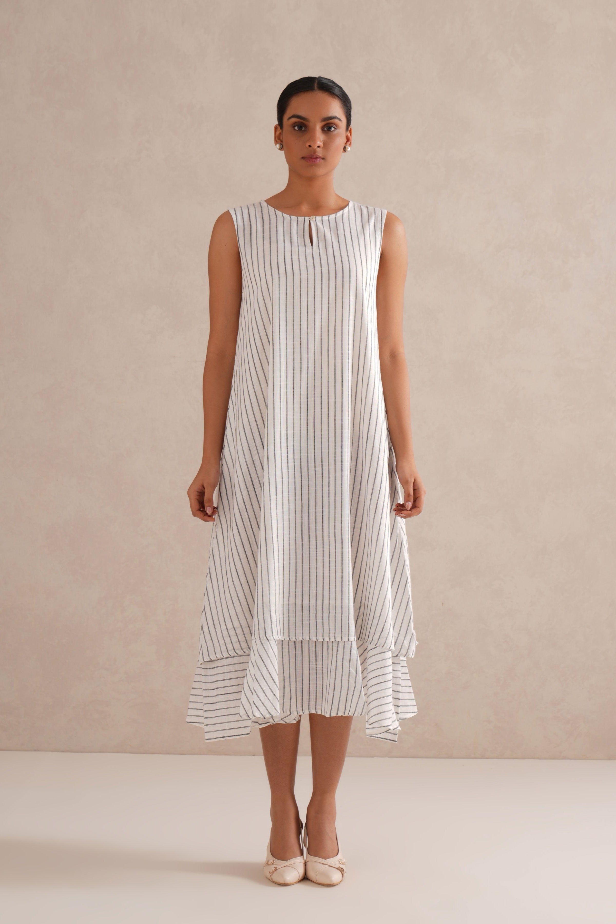 Woman wearing a sleeveless, striped dress against a plain background Woman wearing a sleeveless, striped dress against a plain background