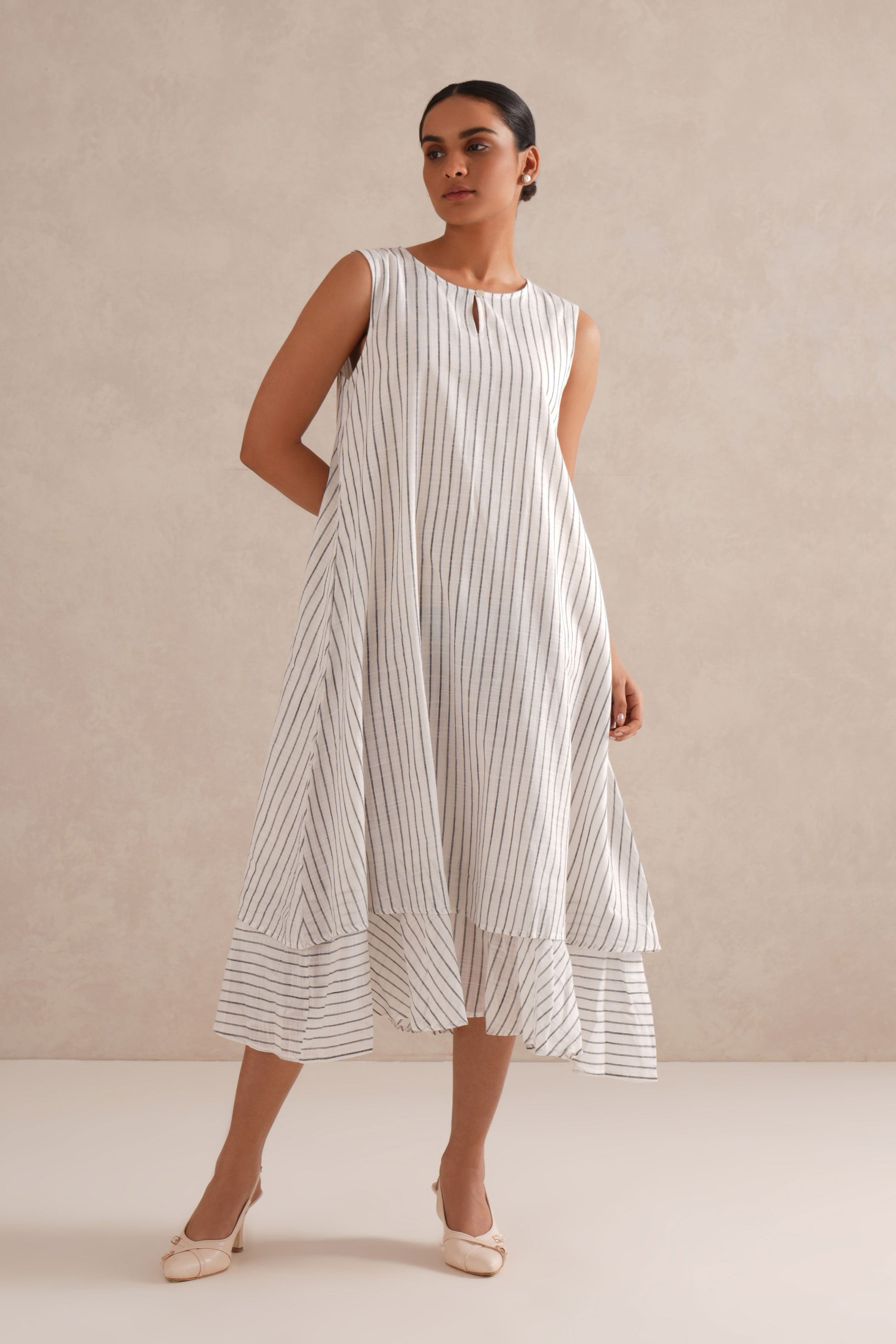 Woman wearing a white dress with black stripes against a beige background Woman wearing a white dress with black stripes against a beige background