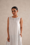 Woman wearing a white dress with black vertical stripes against a beige background Woman wearing a white dress with black vertical stripes against a beige background